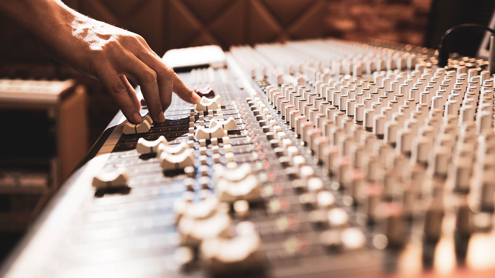 DJ's hand adjusting music on mixer