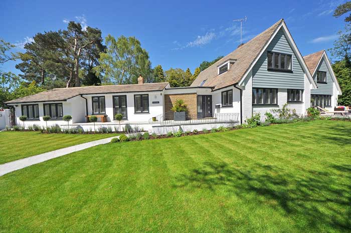 White and blue house with green grass.