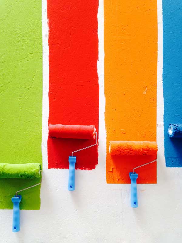 Green paint roller, red paint roller, orange paint roller, and a blue paint roller.