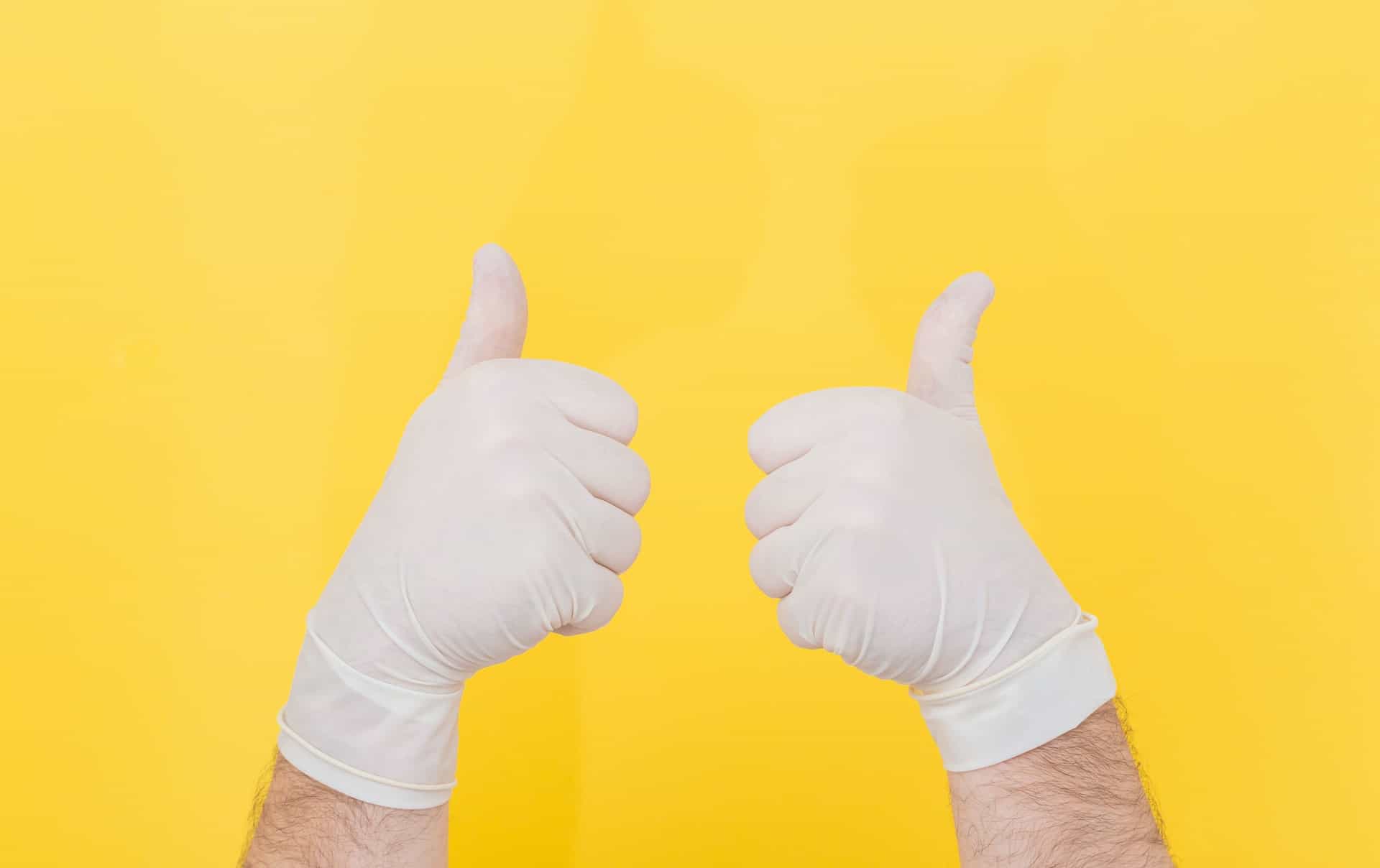 A doctor wearing gloves giving two thumbs up