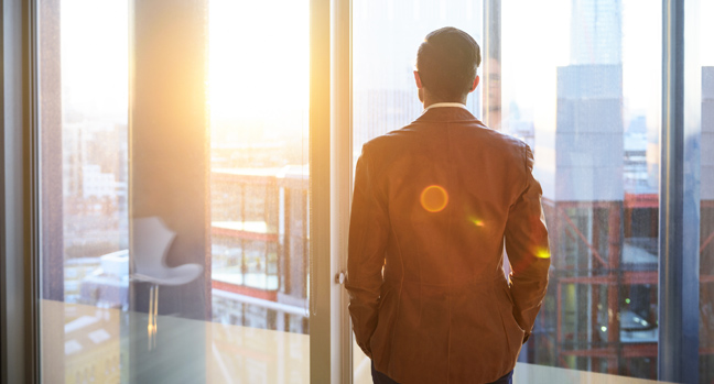Businessman looking out to sunset