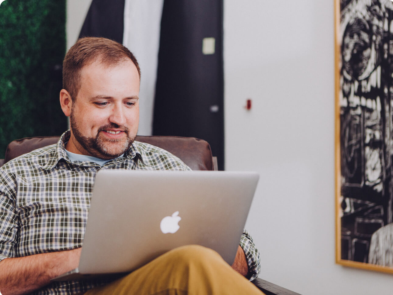 A man smiling while working on a laptop