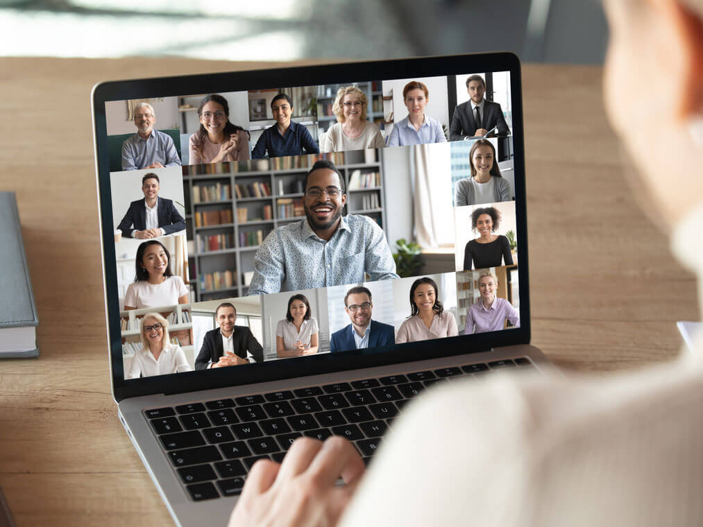 A man stting at his desk attending an online meeting on his laptop