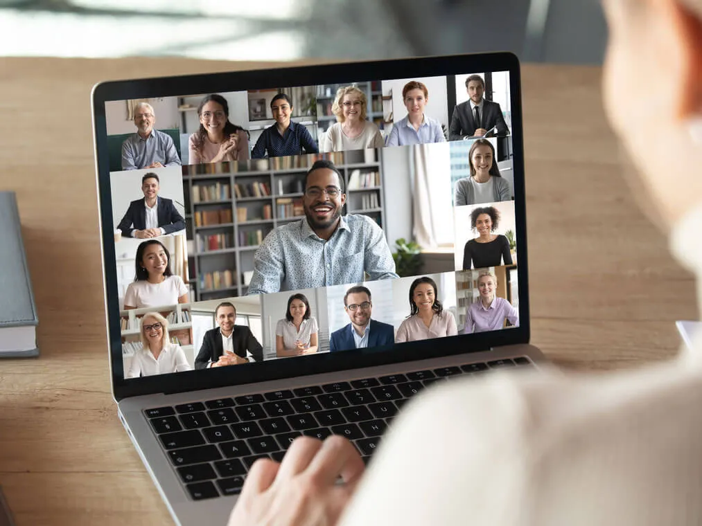 A man stting at his desk attending an online meeting on his laptop