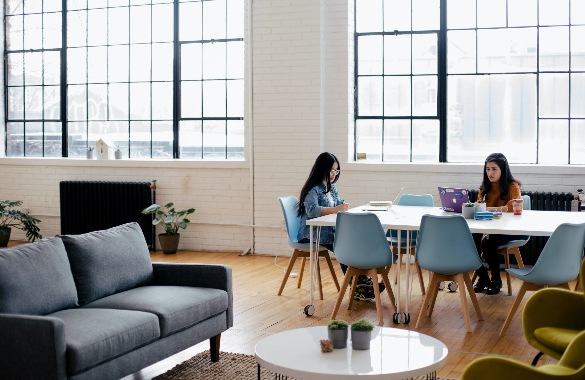 Two women working at a desk in an open plan office