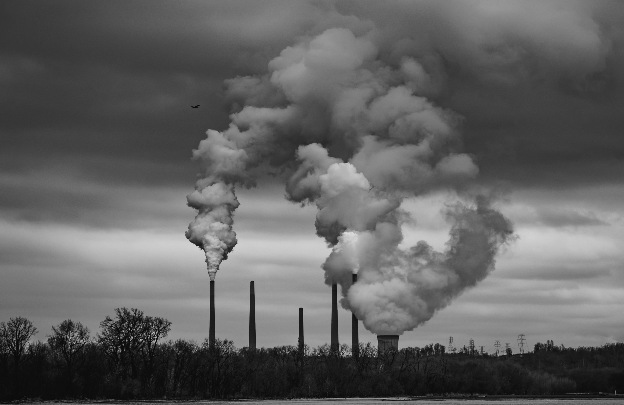 Black and white photo of a powerplant, with smoke billowing into a grey sky.