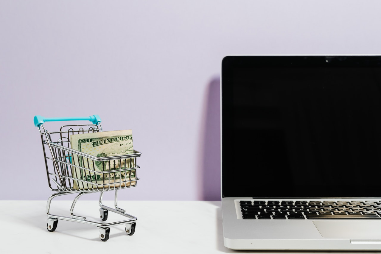 A laptop and miniature trolley with cash in it