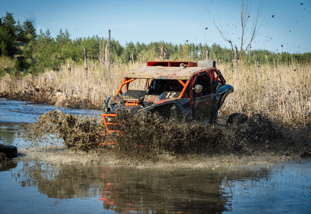 a muddy powersports vehicle taking a headfirst plunge into dirty water