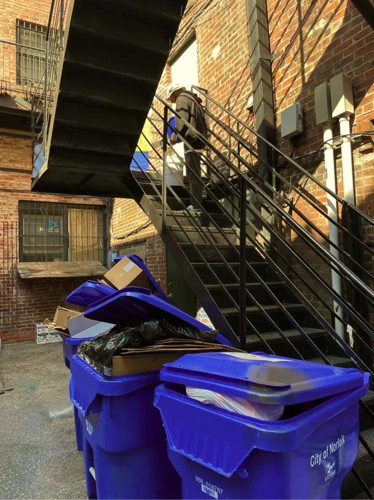 A person on a staircase that is placing food scraps in a bucket