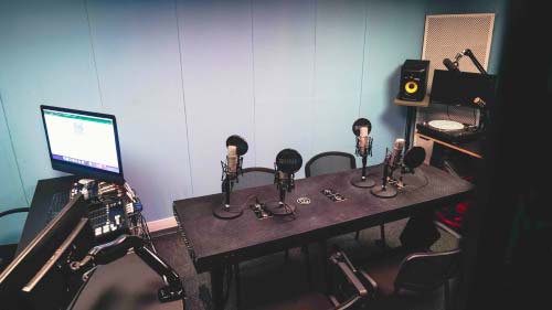 A soundproofed room with a recording setup including computer, microphones and speakers