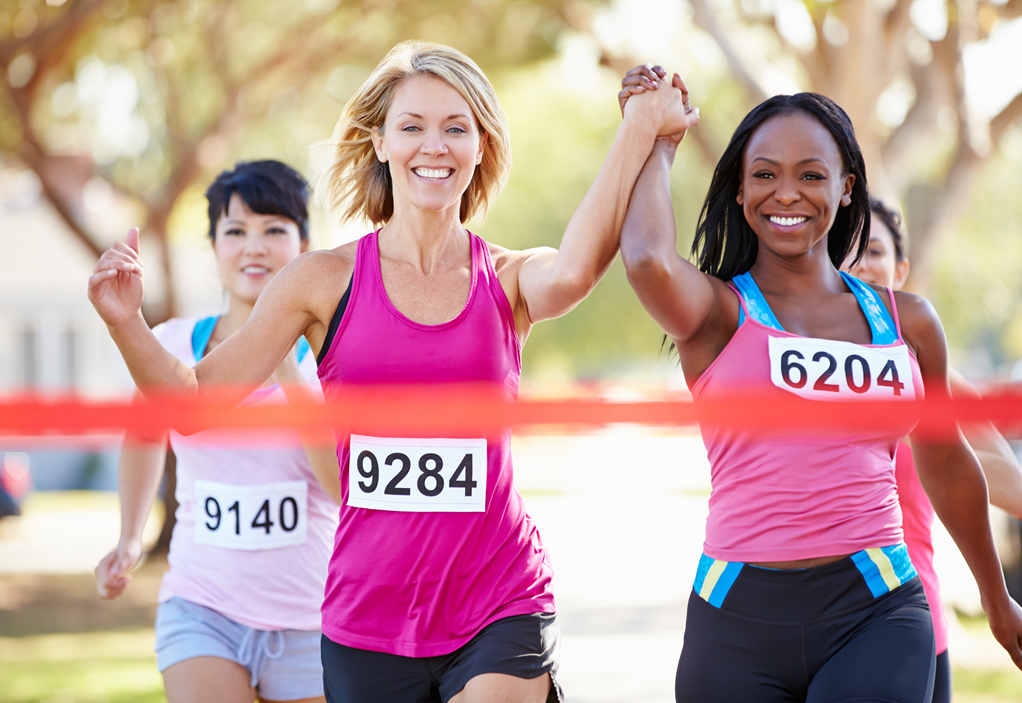 two women crossing finish line together holding hands