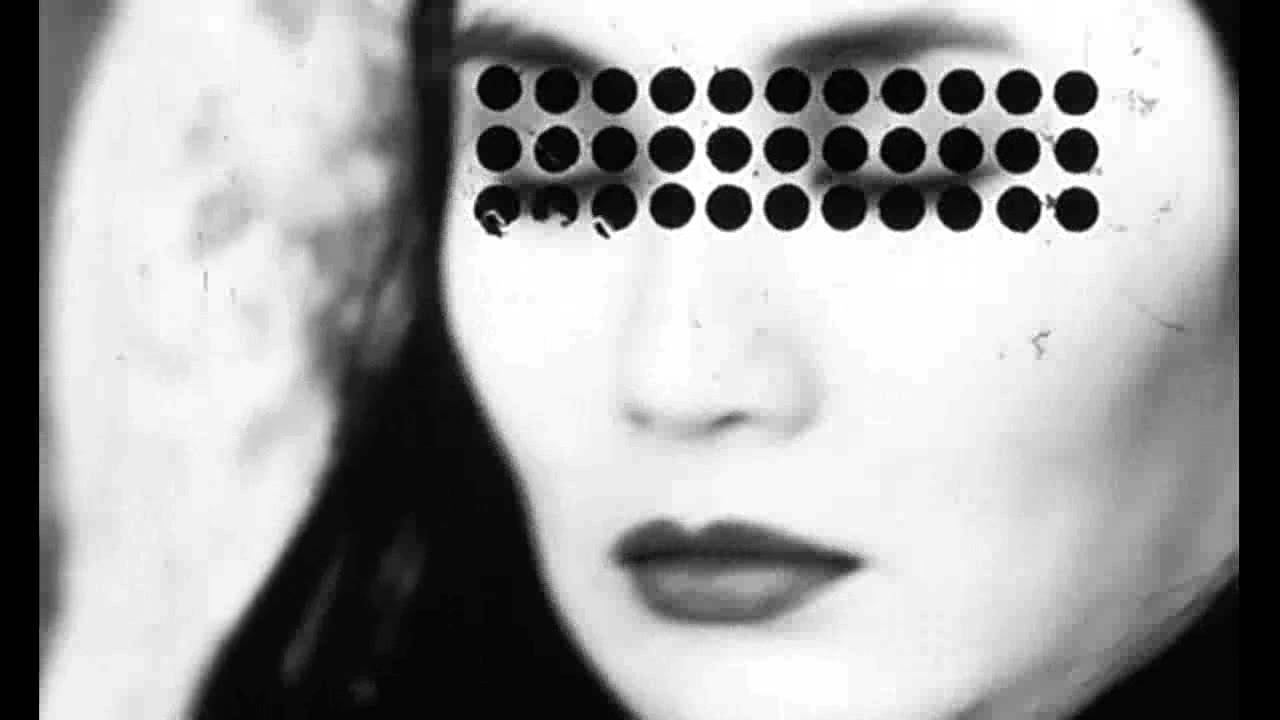 Film still from Irma Vep. A woman with closed eyes and lipstick. Three rows of dots cover her eyebrows and eyes.