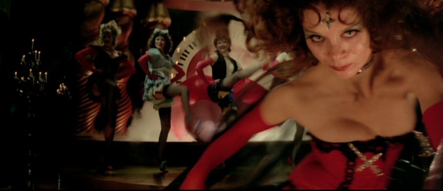 Film still from Lisztomania. A line of cabaret dancers with their legs kicking up. A woman in a corset and gloves approaches the camera seductively.