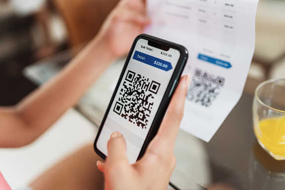 A mobile phone being used to scan a QR code on a bill.