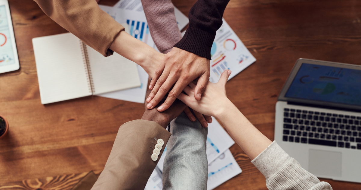 Image of team putting hands together during meeting