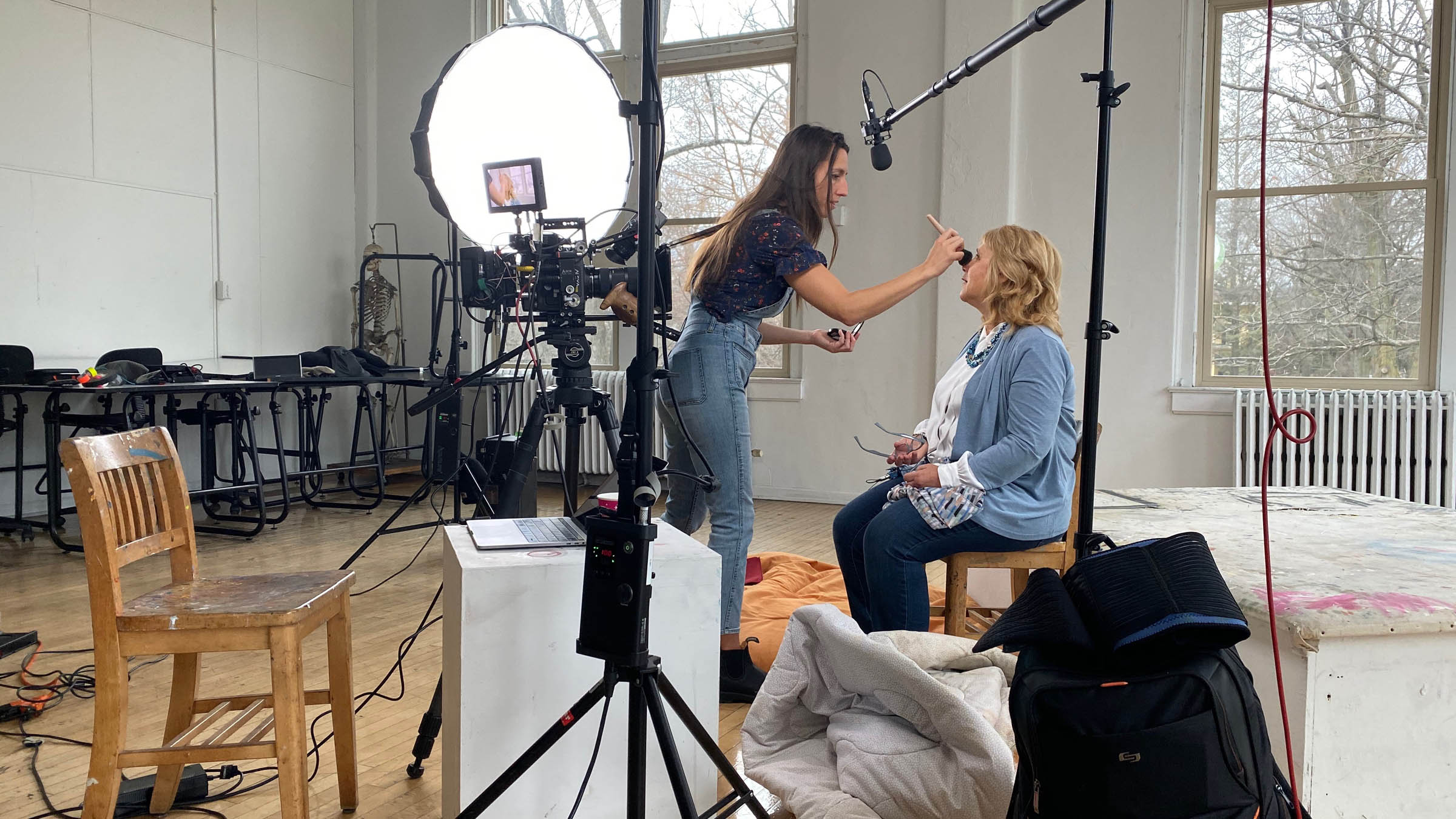 a stylist touching up an actresses makeup on set