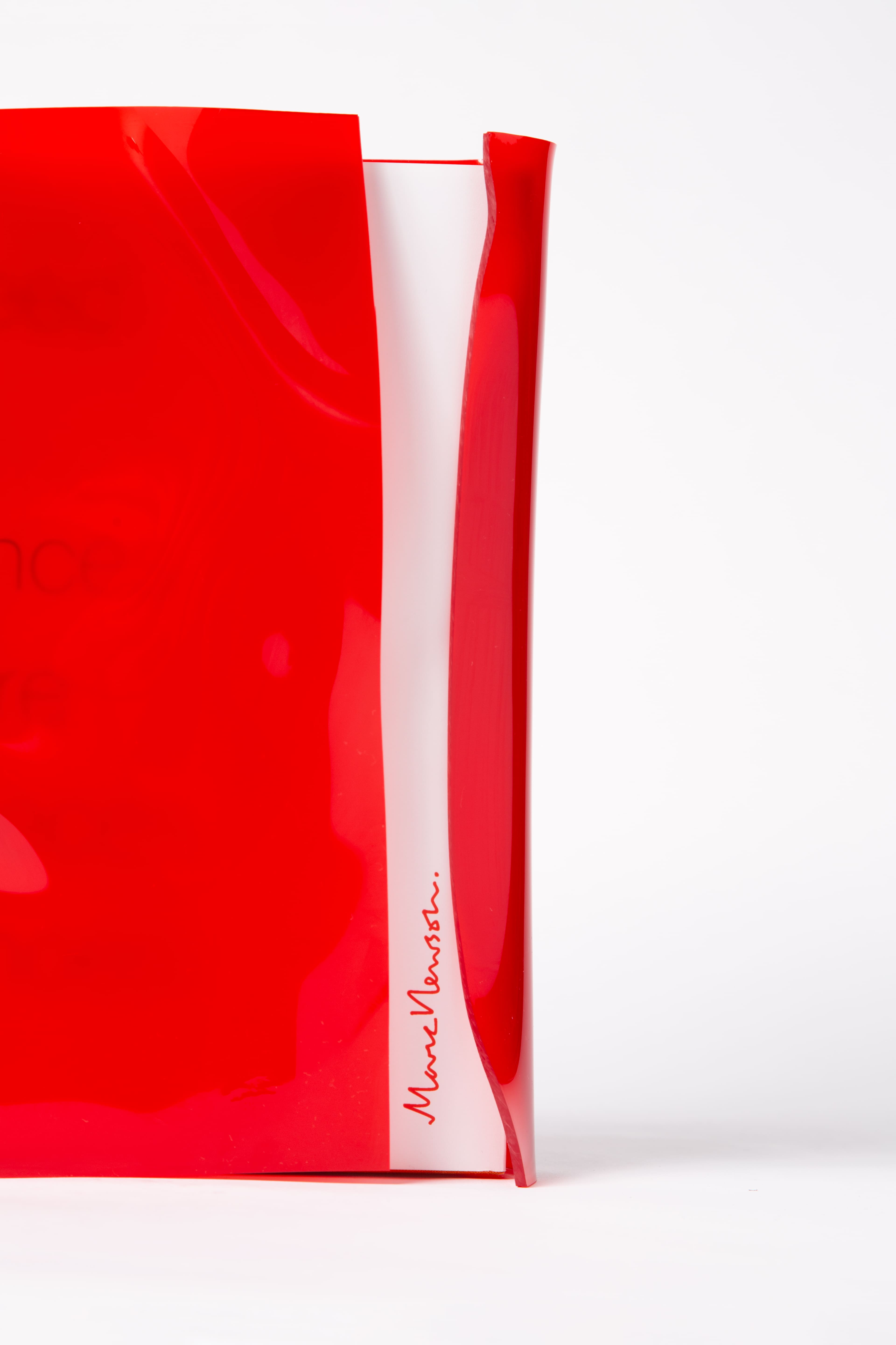Detail close up of a hardcover book inside a red acrylic slipcase. The name of the book is in red.