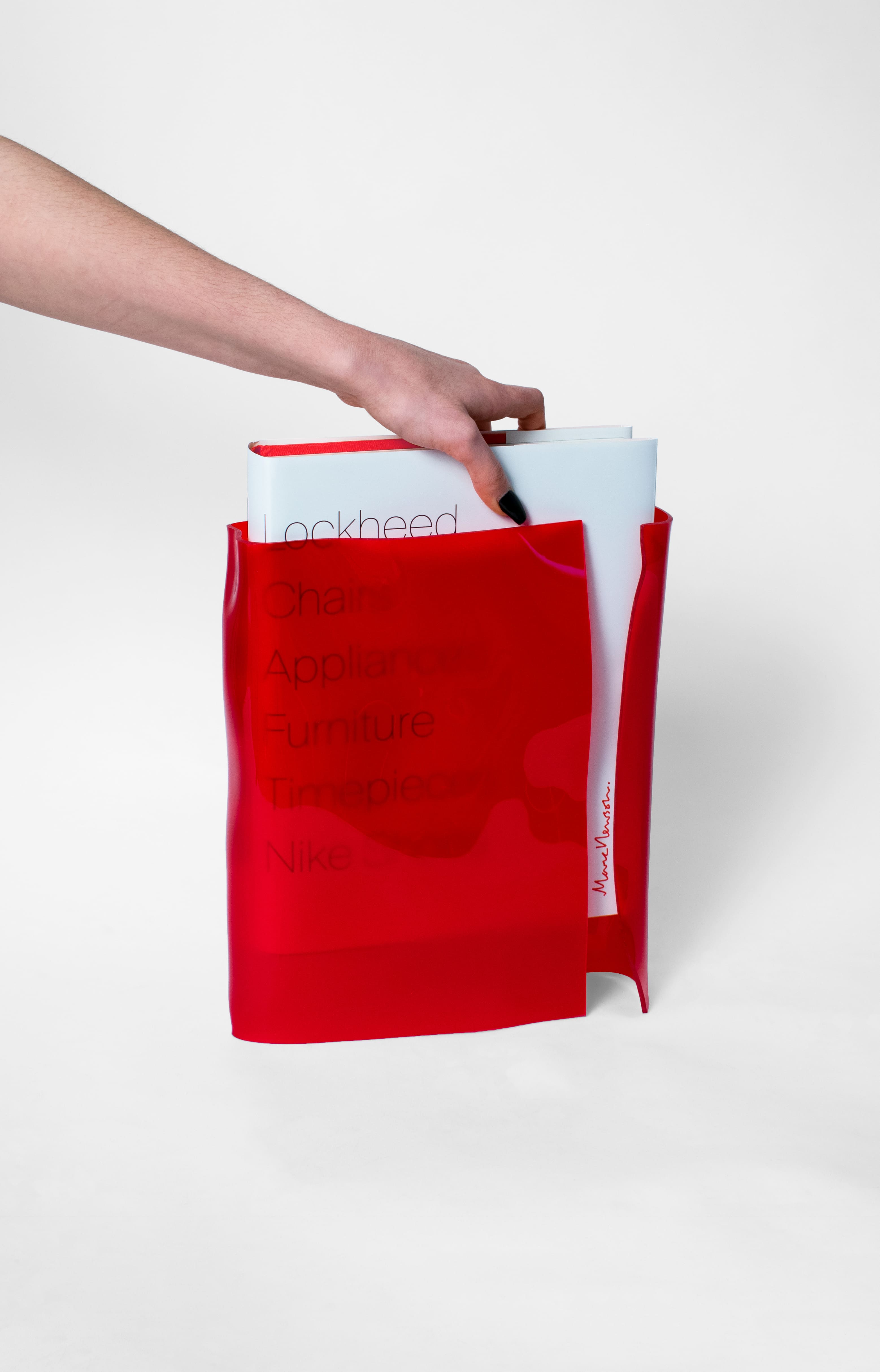 Hand slipping a hardcover book out of a red acrylic slipcase.