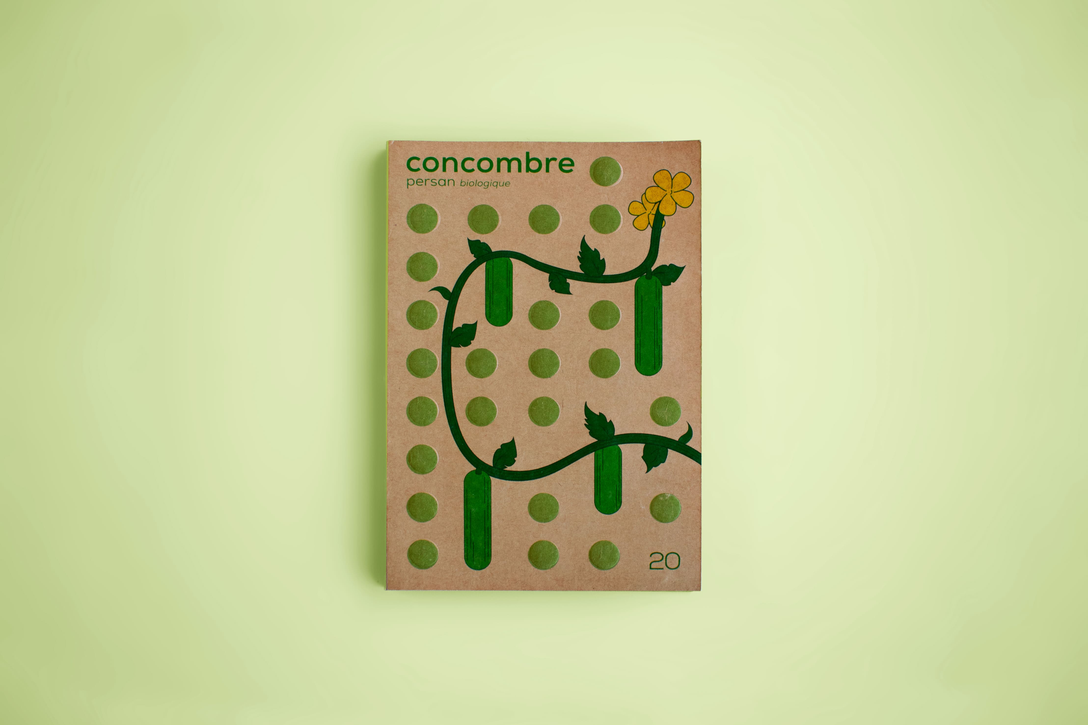 A cucumber seed packaging made from Kraft paper with green embossed circles. It is on a green background.