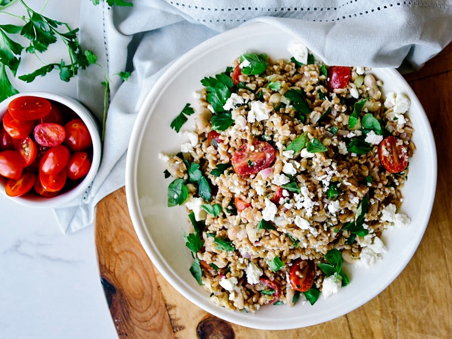 Bowl of wheat berry salad with a side of tomatoes.