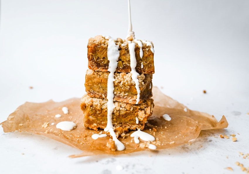 Stack of pumpkin pie bars with a drizzle of decadent icing.