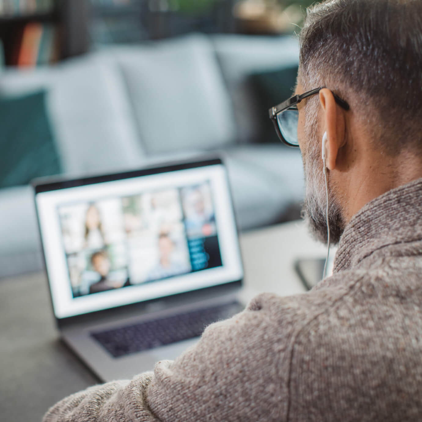 A man is connected to Duratus Inner Circle on his laptop. He has his earphones in.