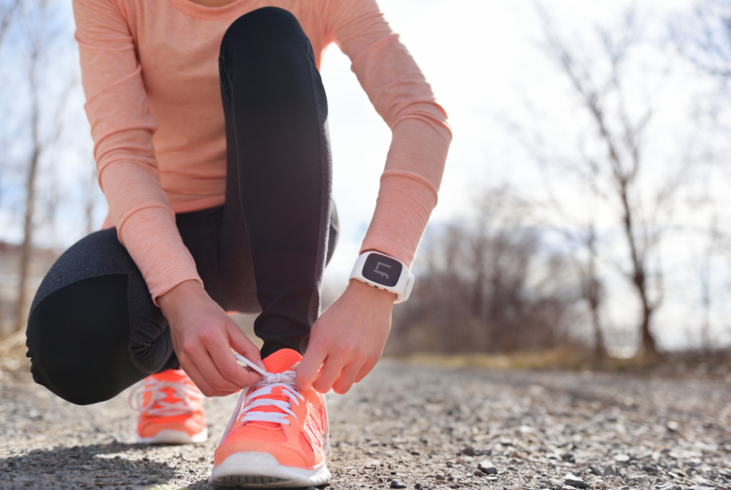 woman wearing smartwatch tying shoes on a run