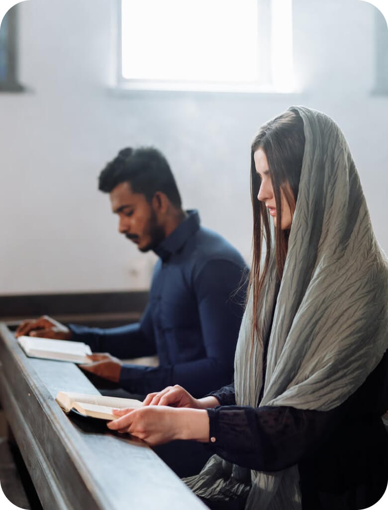 Man and woman reading a book while sitting on pews