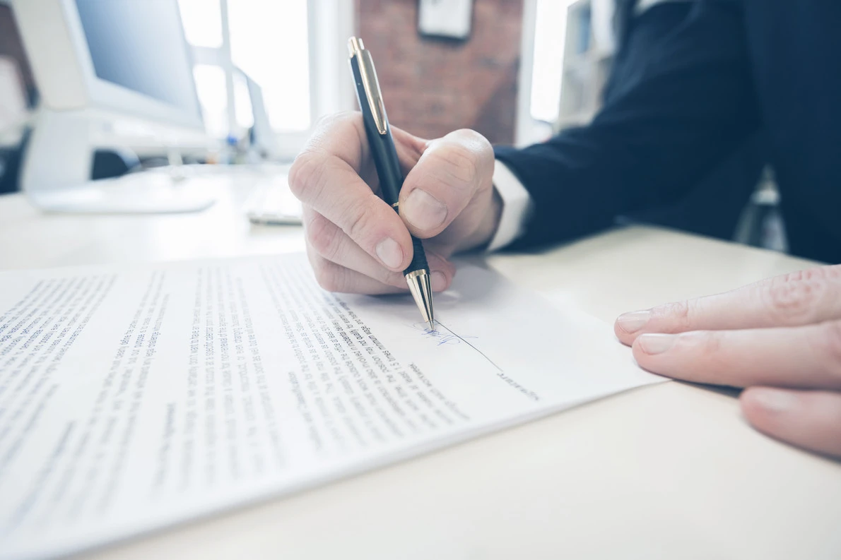 businessman signing a contract on a white table