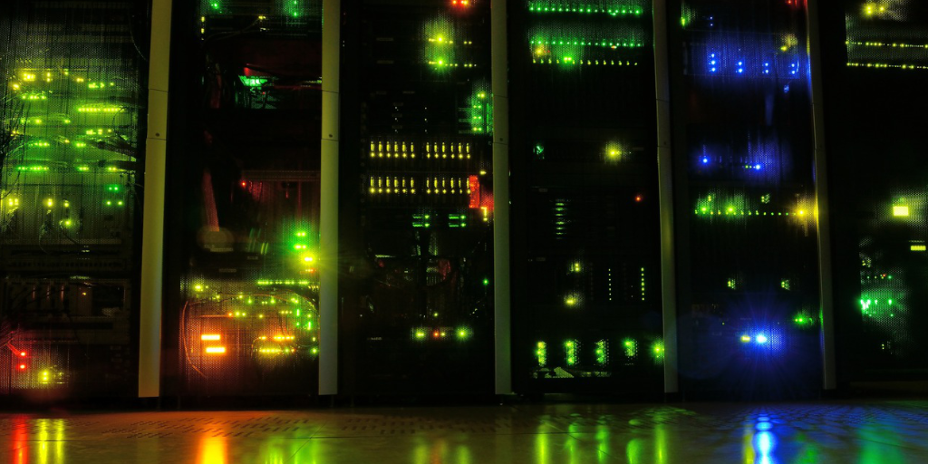 A server stack akin to one running EC2 instances. The lighting is dim, with the servers' lights glowing in the gloom.