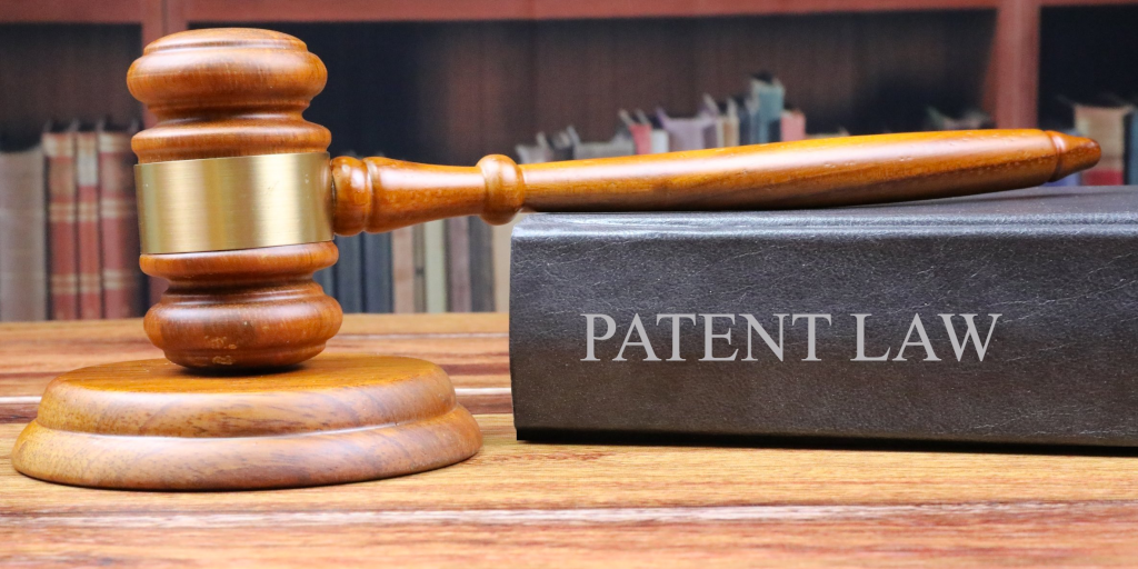 A photo of a gavel resting on a thick book, which has "PATENT LAW" written on its spine