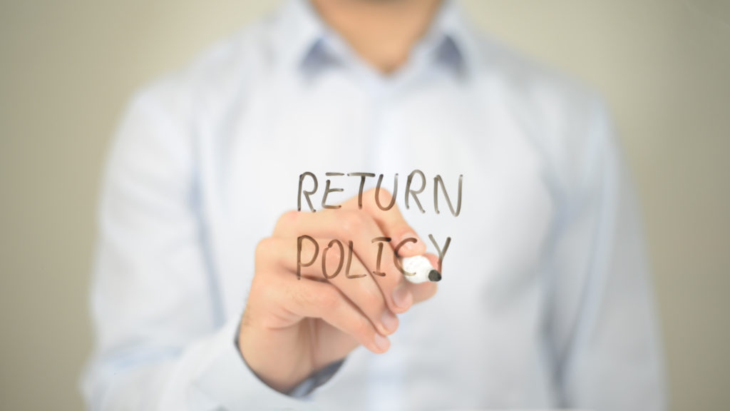 A man in a collared shirt writing the words: return policy.