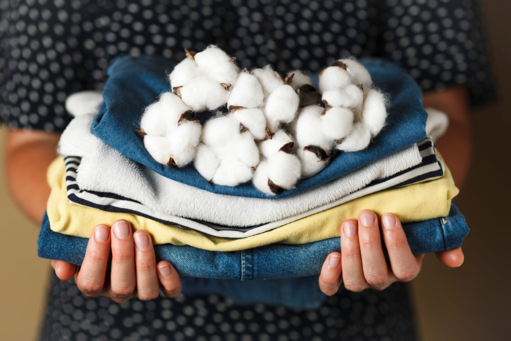 Hands holding clothing made with cotton, contributing to fashion's water footprint