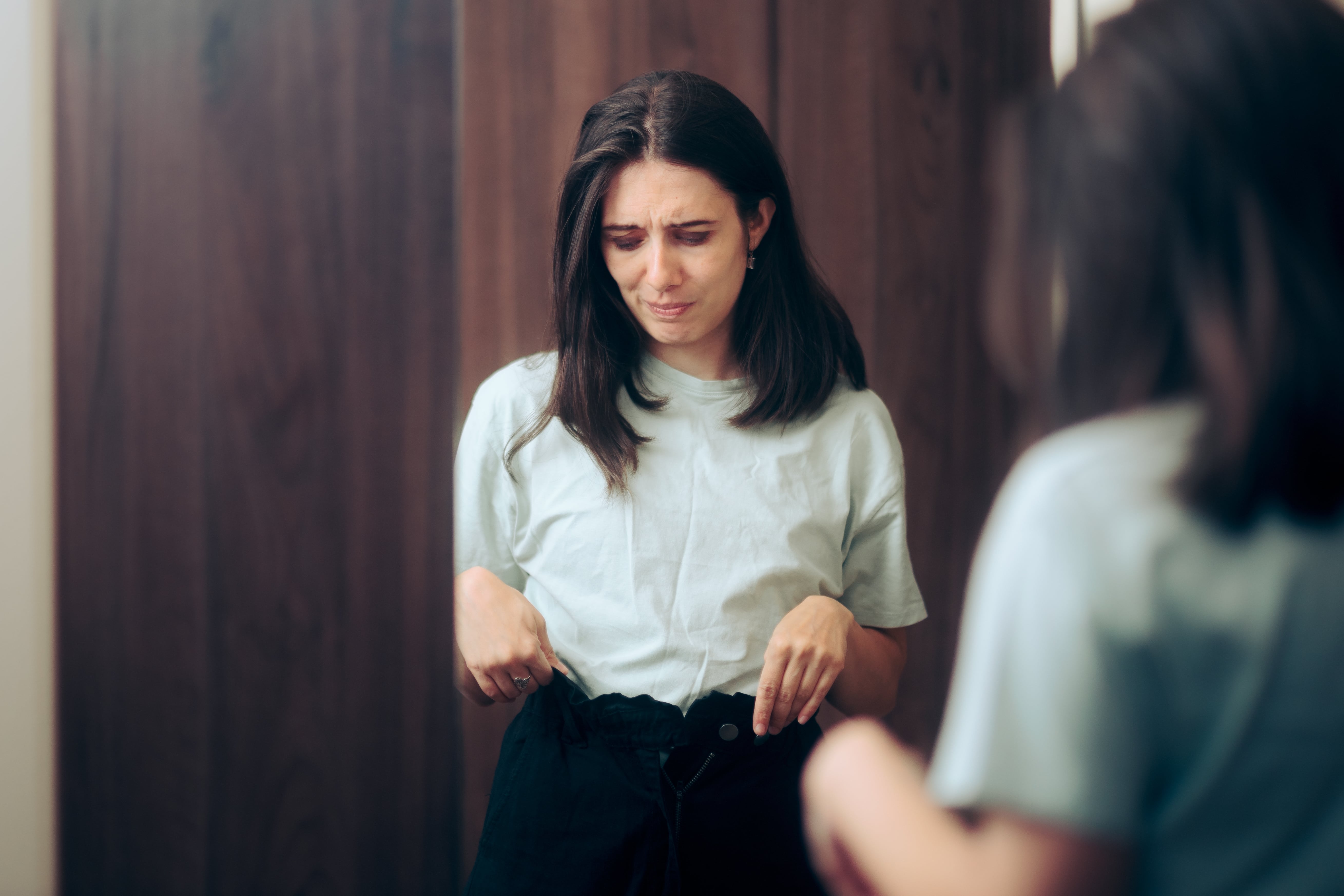 A female shopper trying on jeans that do not fit right due to vanity sizing