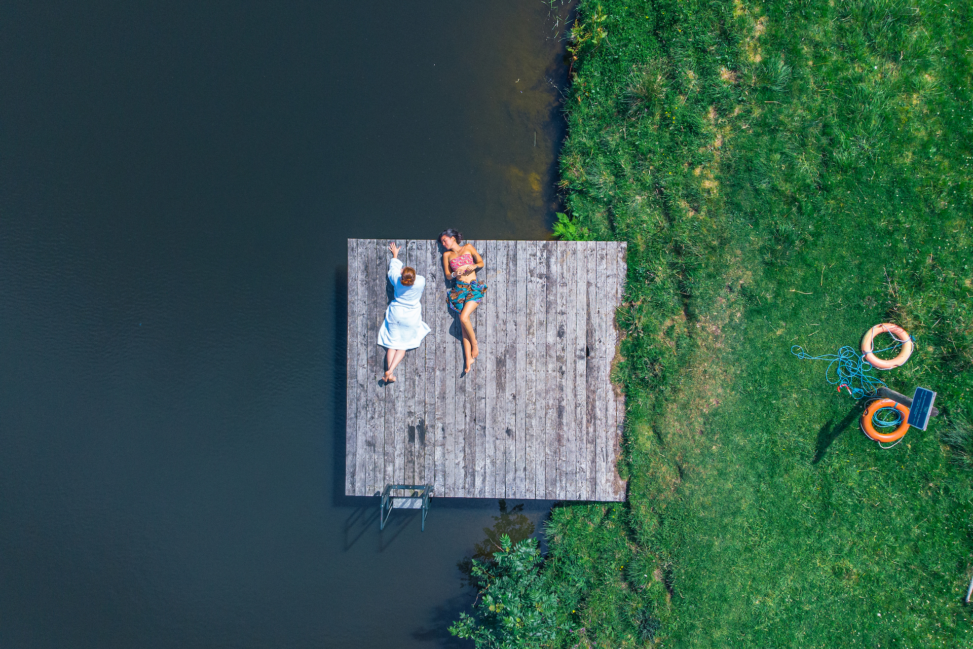 Two people sunbathing on the swim platform on the Broughton Hall estate.