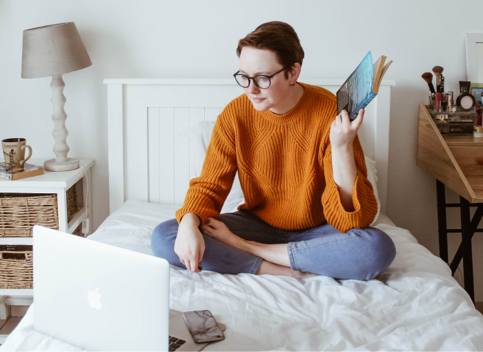 a person sitting on a bed with a laptop