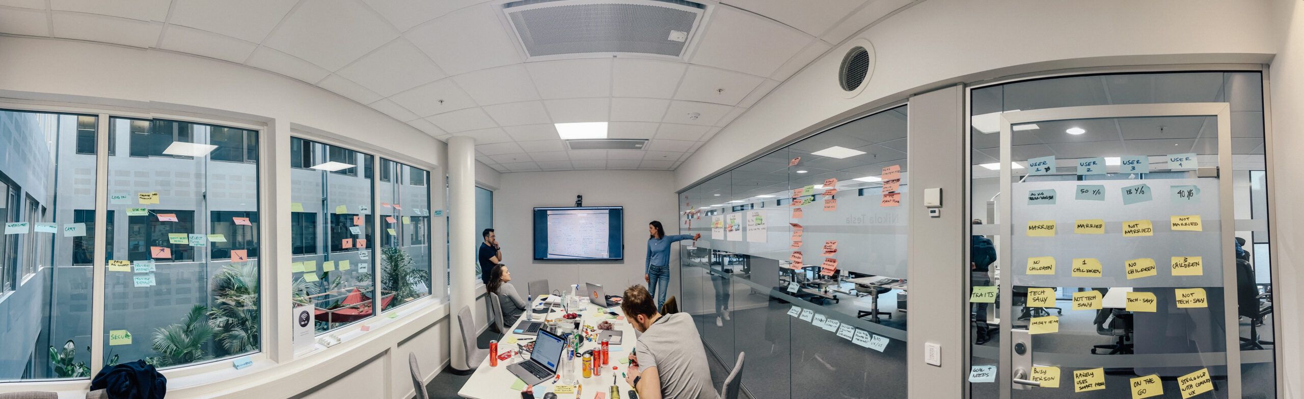 Neonomics employees sitting in the design sprint room, covered with postit's