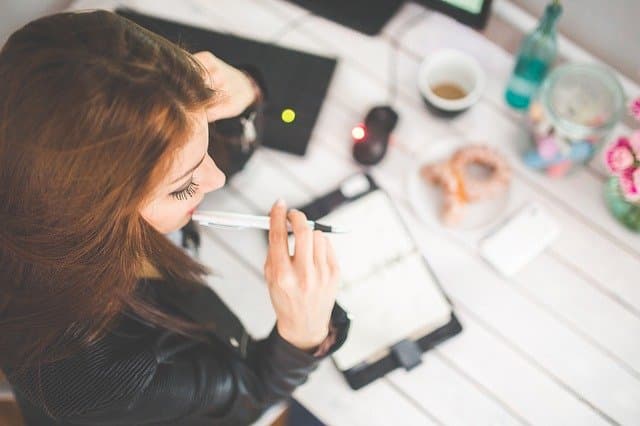 Femme qui réfléchi devant un cahier