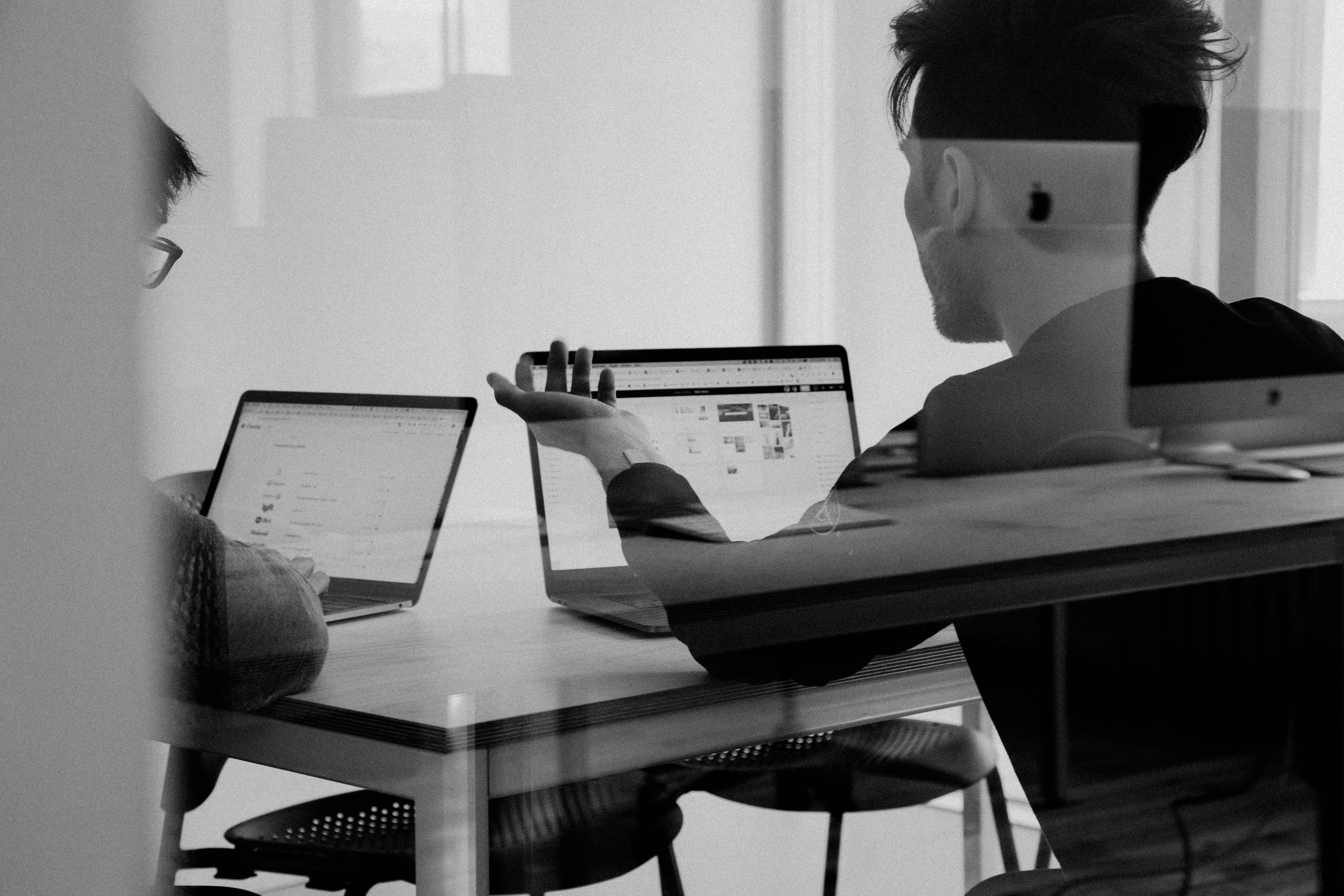 Two colleagues working together with laptops