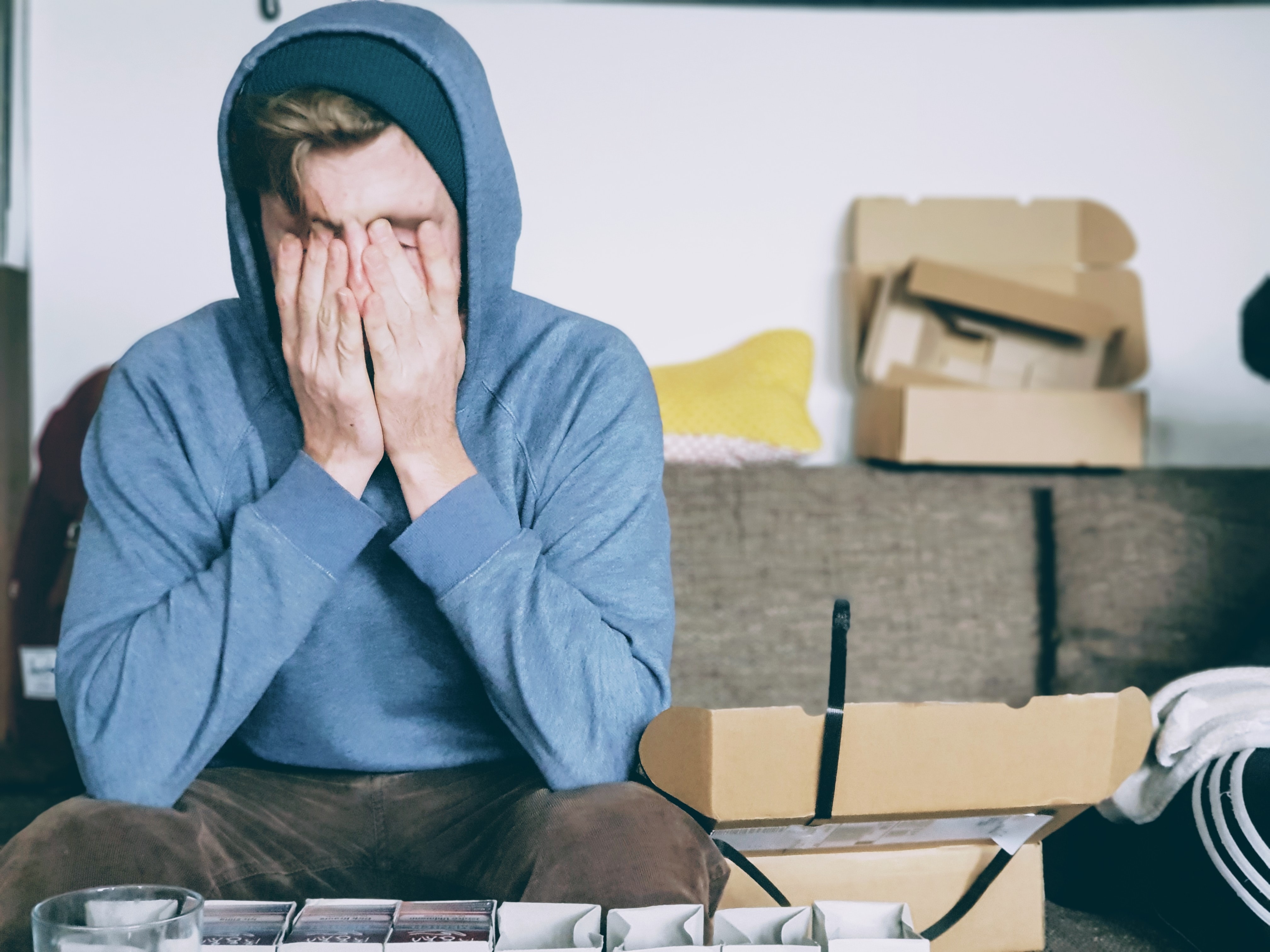 a guy in a blue hoody sitting on a sofa, tired