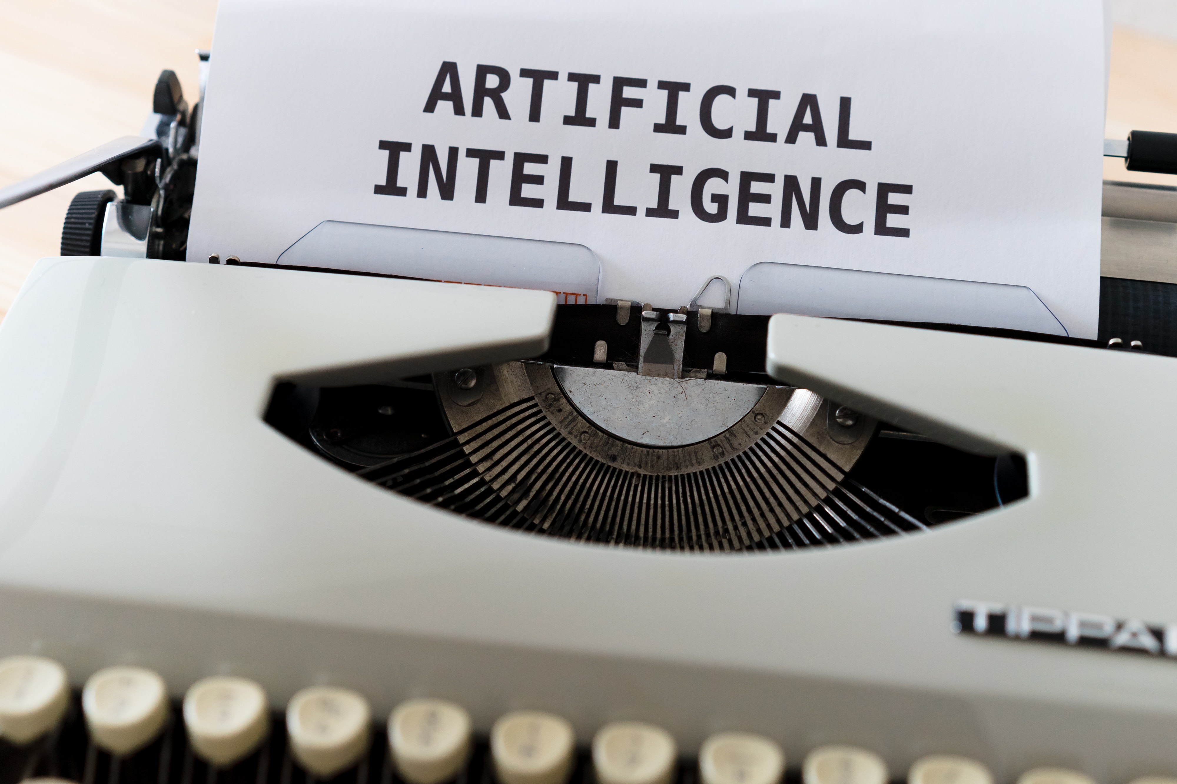 typewriter with a paper on which is written artificial intelligence.