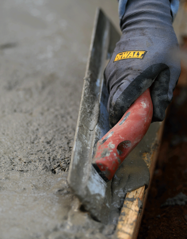 contractors hand using a trowel to finalize details on a concrete driveway