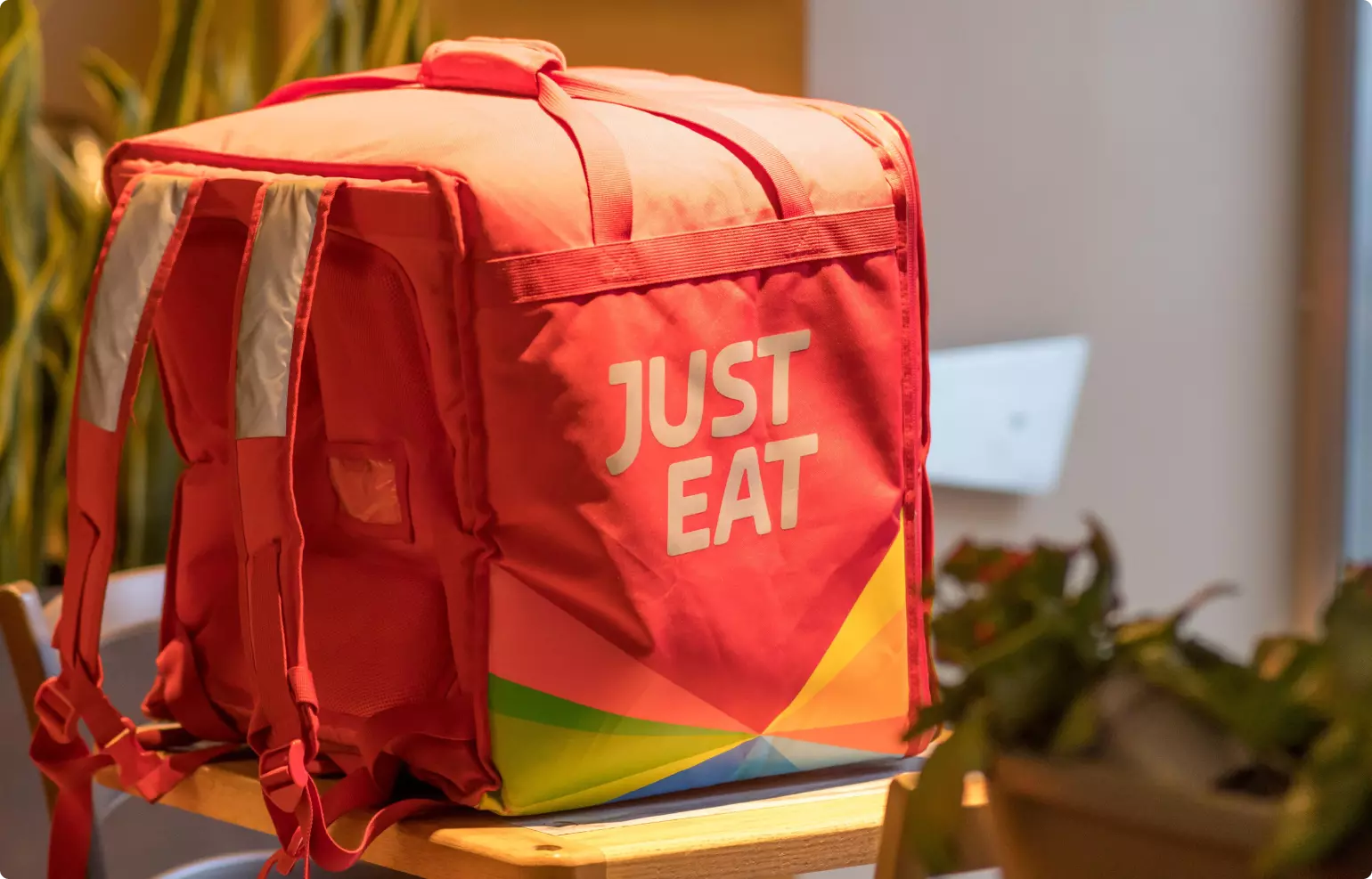 A large, red, square food delivery backpack with "Just Eat" branding.