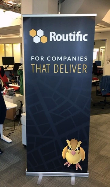A Routific company banner in an office space. It has a Pokemon character in the bottom left hand corner.