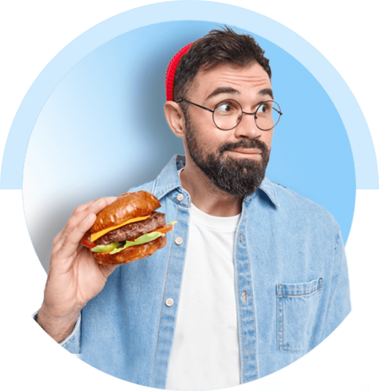 Hombre con anteojos y una hamburguesa en mano.