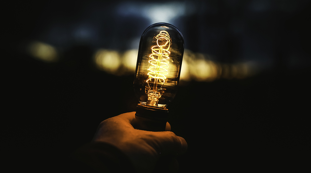 Image of a person holding a light bulb in the dark at night