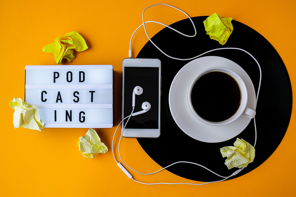 Image of a cup of coffee, airpods and iphone , podcast