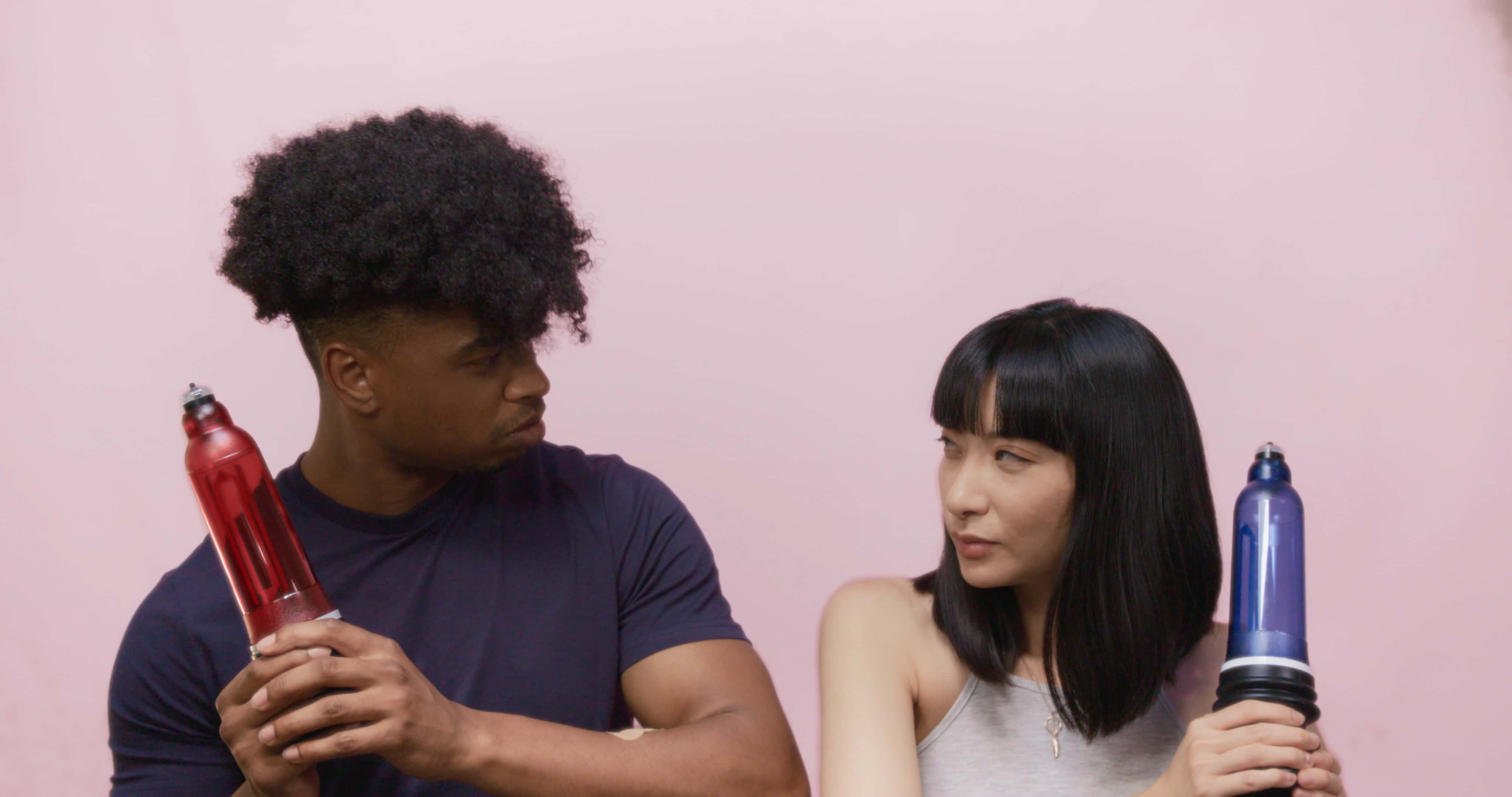 man and women holding Bathmate penis pumps like swords going into battle