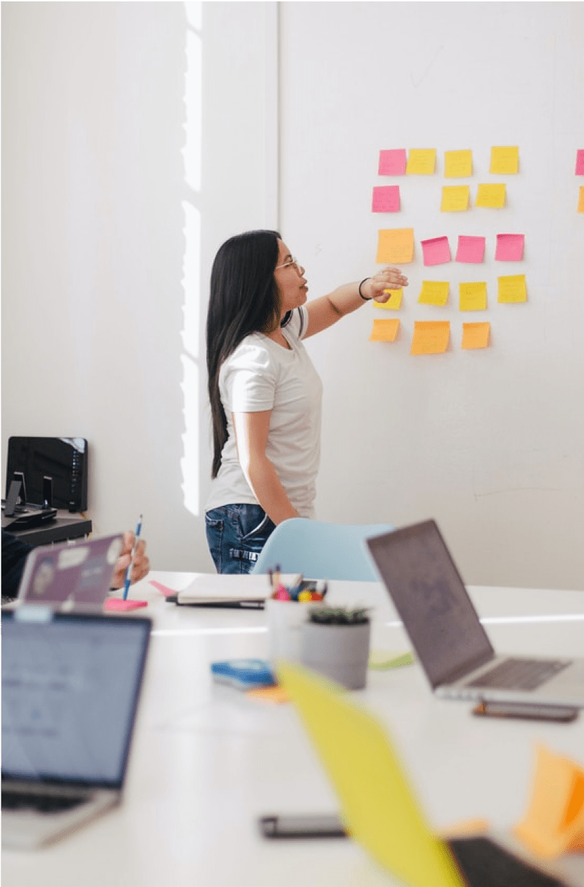 Person pointing to sticky notes on a whiteboard.