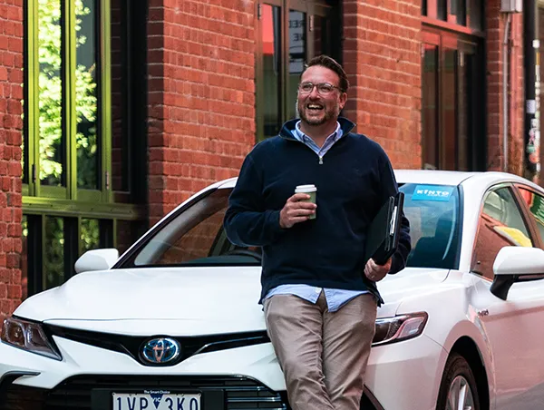Man holding coffee cup in front of the car